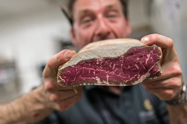 Ein Mann hält ein Stück Fleisch.