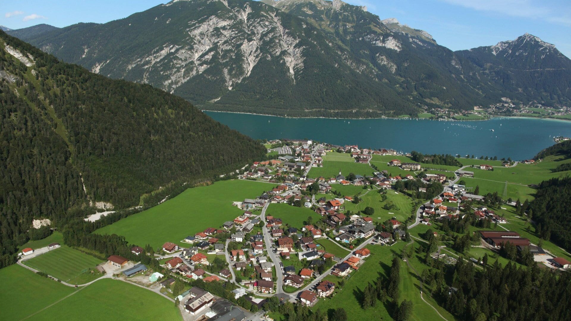 Landschaft mit Bergen, Dorf und See