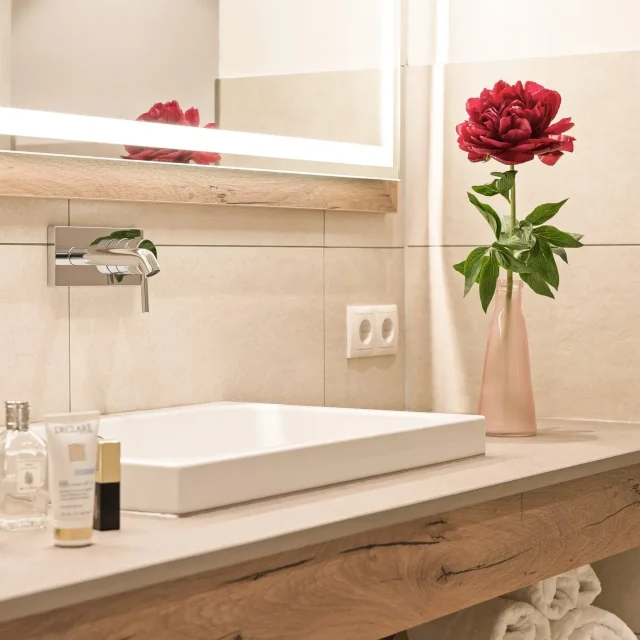Modernes Badezimmer mit Blumen und Pflegeprodukten.