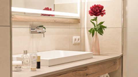 Modernes Badezimmer mit Blumen und Pflegeprodukten.