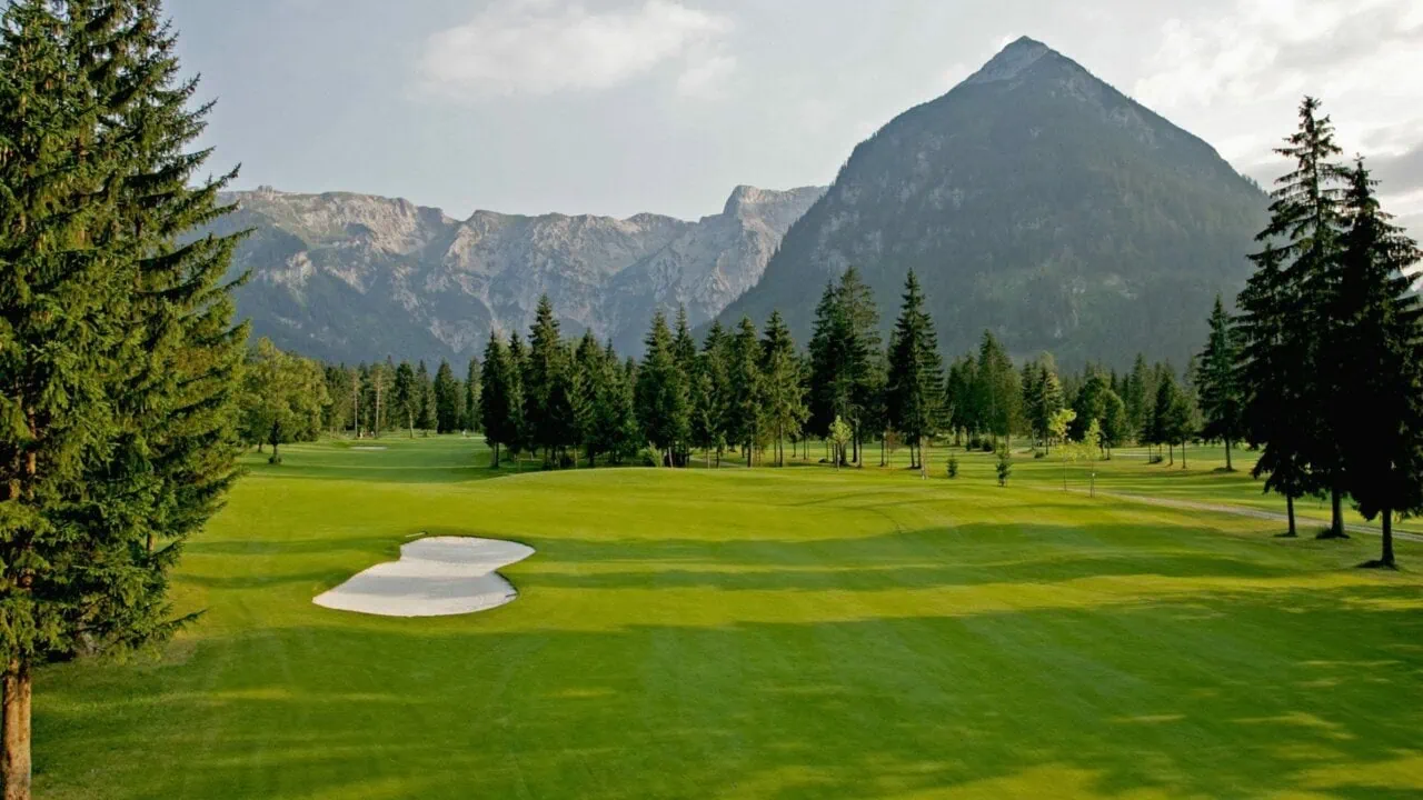 Golfplatz mit Bergen und Bäumen im Hintergrund