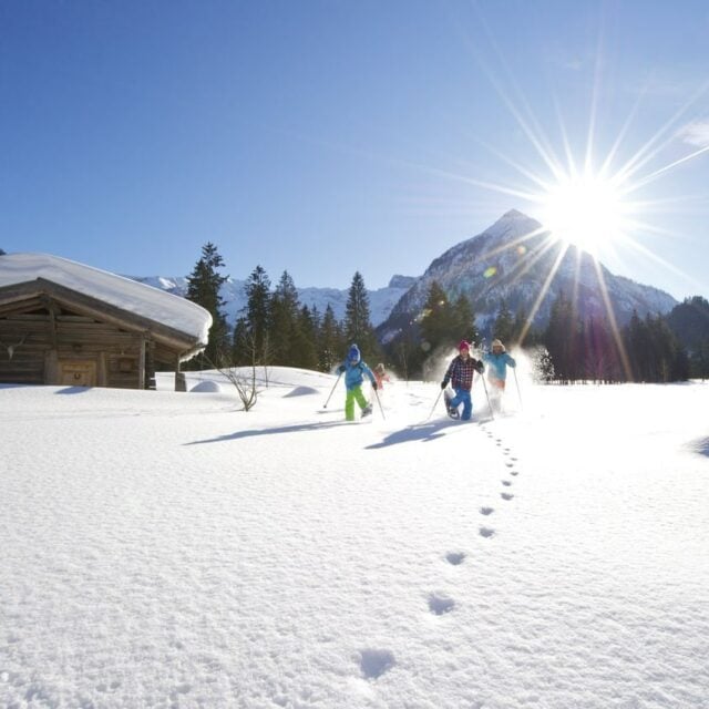 Kinder im Schnee mit Sonnenschein und Bergen