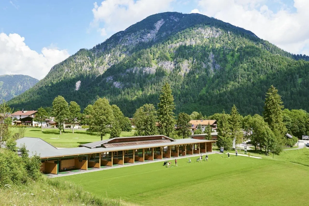 Golfplatz mit Bergen und Bäumen im Hintergrund.