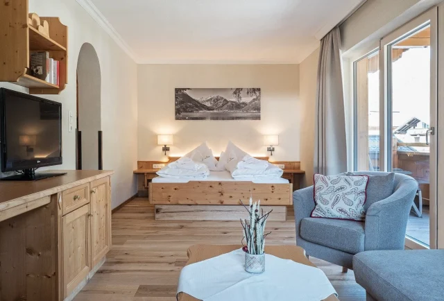 Gemütliches Hotelzimmer mit Holzmöbeln und Fenstern.