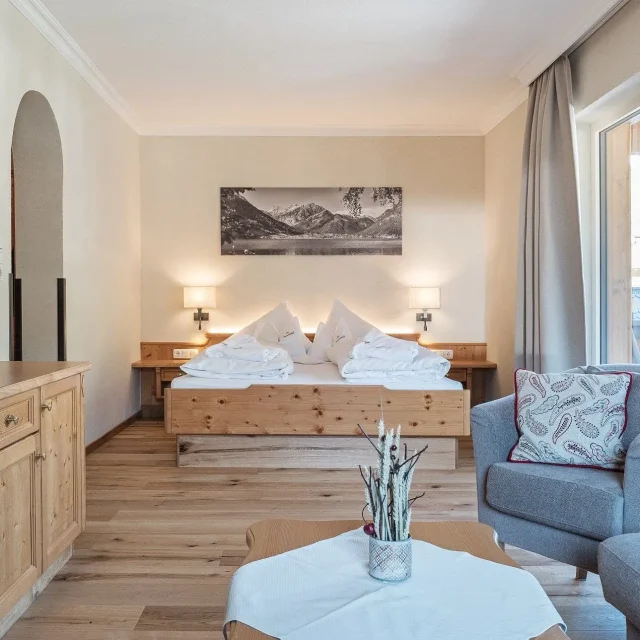 Gemütliches Hotelzimmer mit Holzmöbeln und Fenstern.