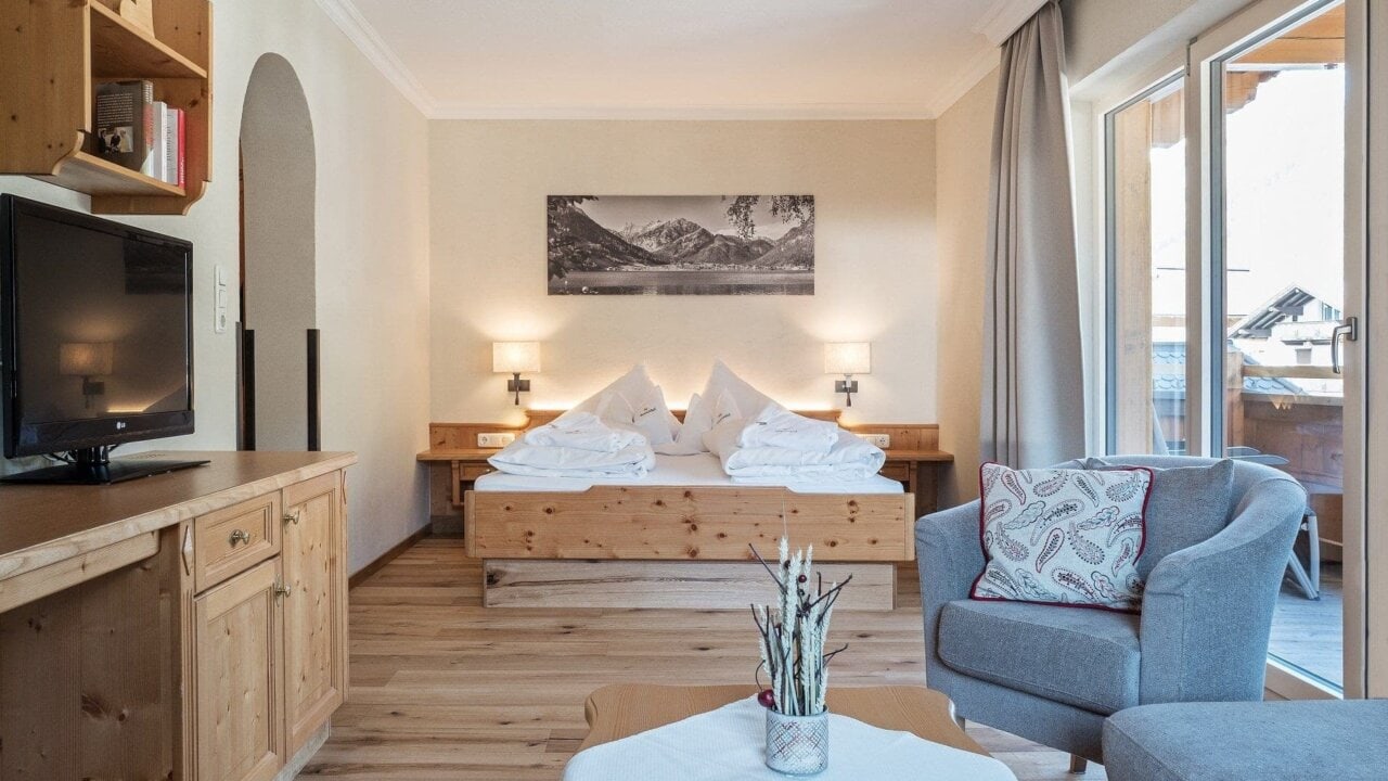 Gemütliches Hotelzimmer mit Holzmöbeln und Fenstern.