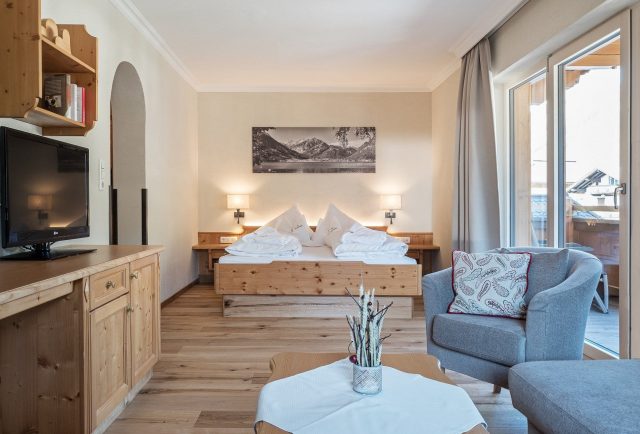 Gemütliches Hotelzimmer mit Holzmöbeln und Fenstern.