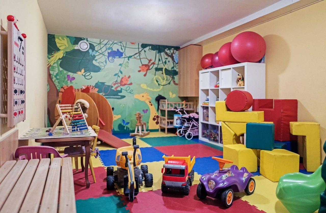Bunte Spielzimmer mit Spielsachen und Matten.
