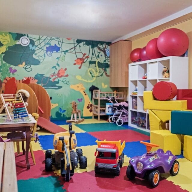 Bunte Spielzimmer mit Spielsachen und Matten.