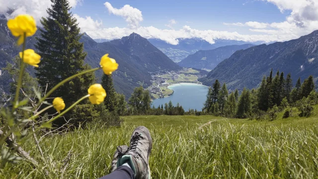 Wanderer blickt auf Bergsee und Berge.