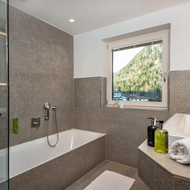 Helles Badezimmer mit Tuben und Aussicht auf Berge.
