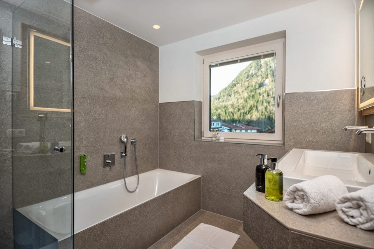 Helles Badezimmer mit Tuben und Aussicht auf Berge.