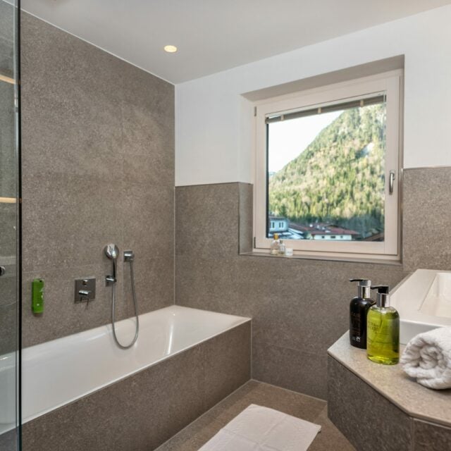 Helles Badezimmer mit Tuben und Aussicht auf Berge.