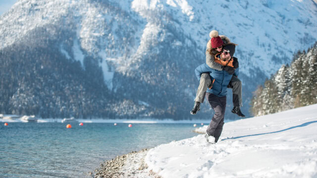 Paar beim Spielen im Schnee am See.