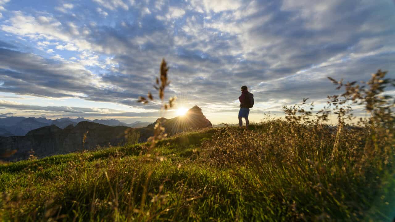 Wanderer im Bergpanorama bei Sonnenuntergang.