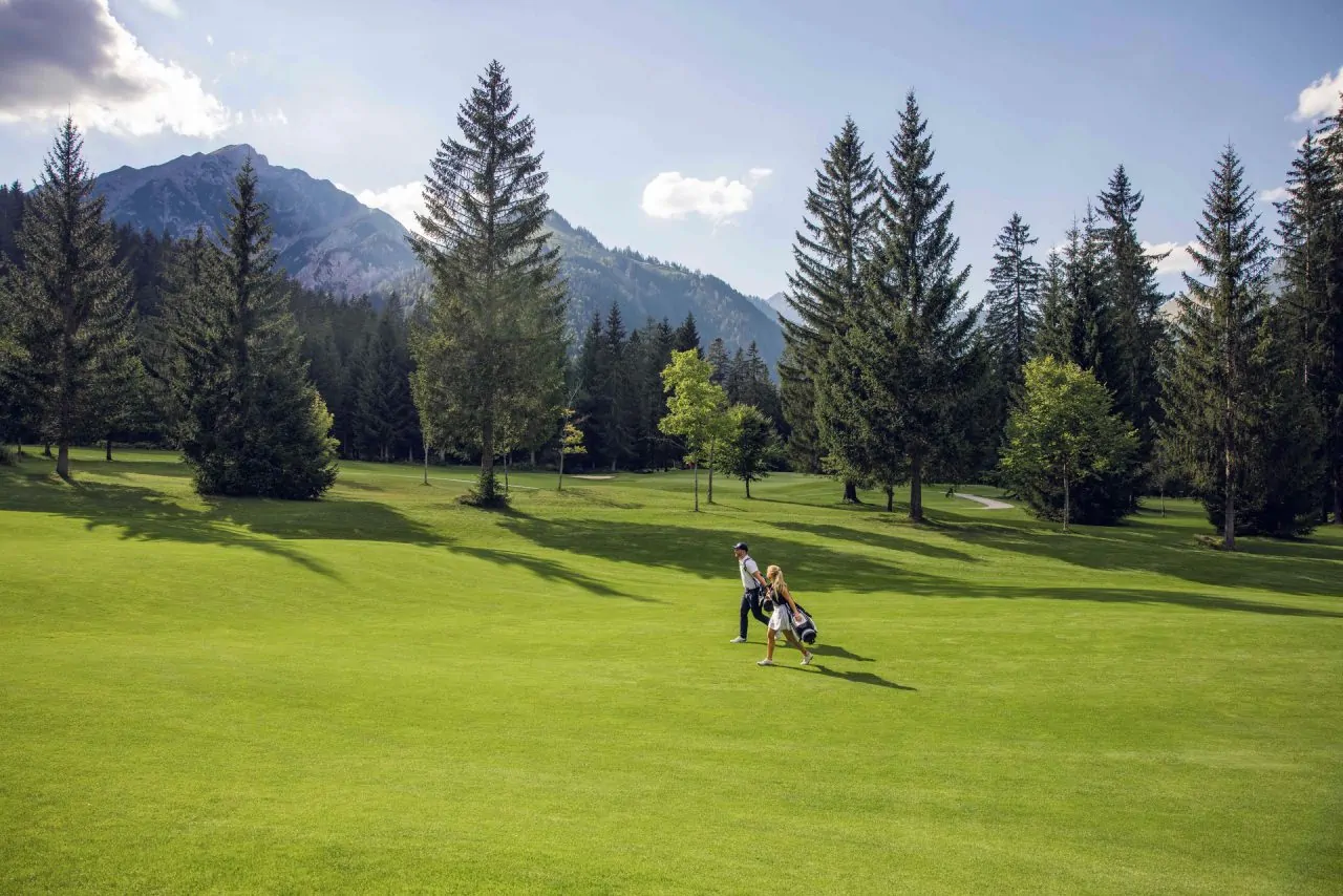 Golfspieler auf einem grünen Platz in den Bergen.