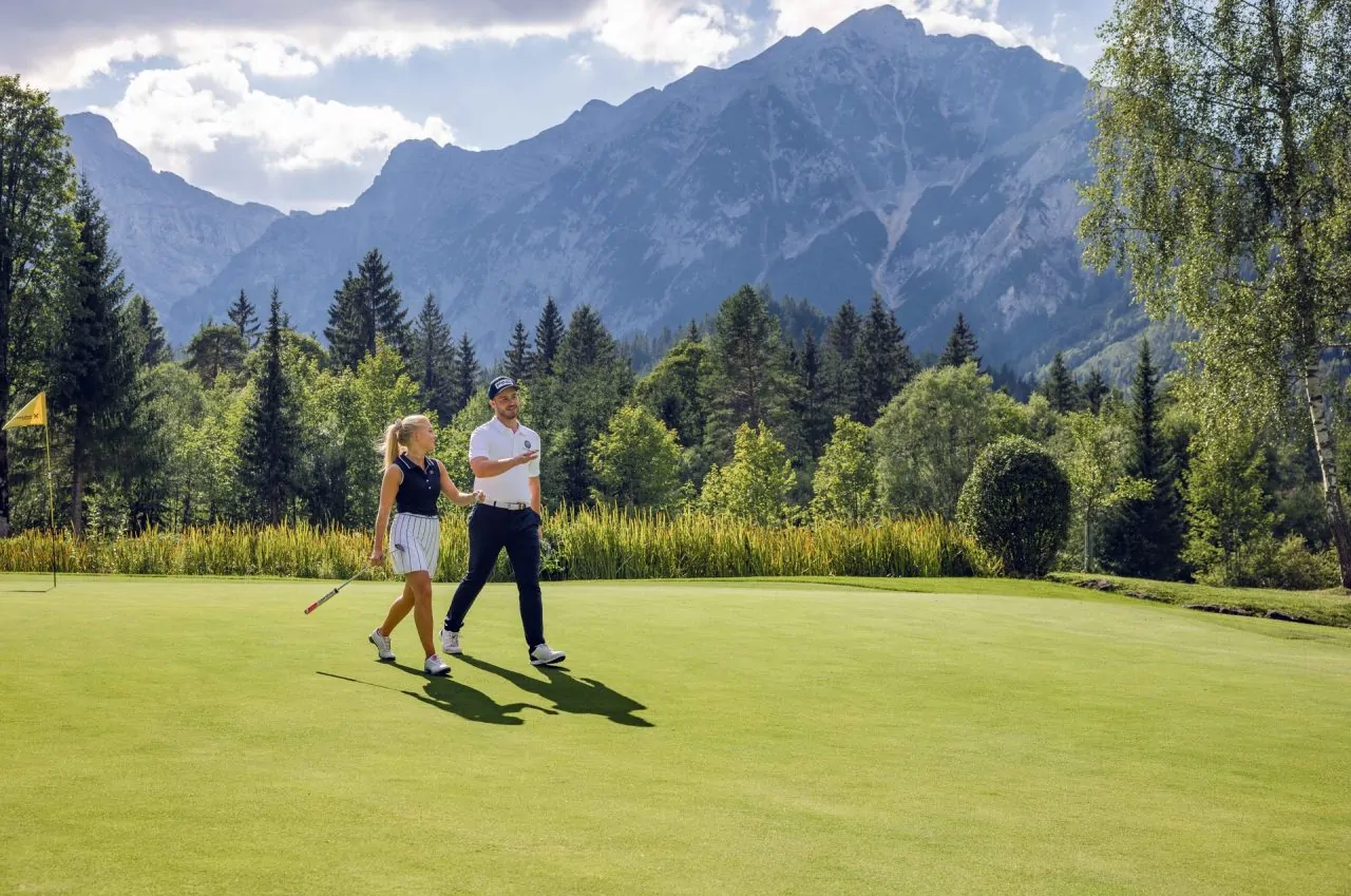 Paar geht über einen Golfplatz in den Bergen.