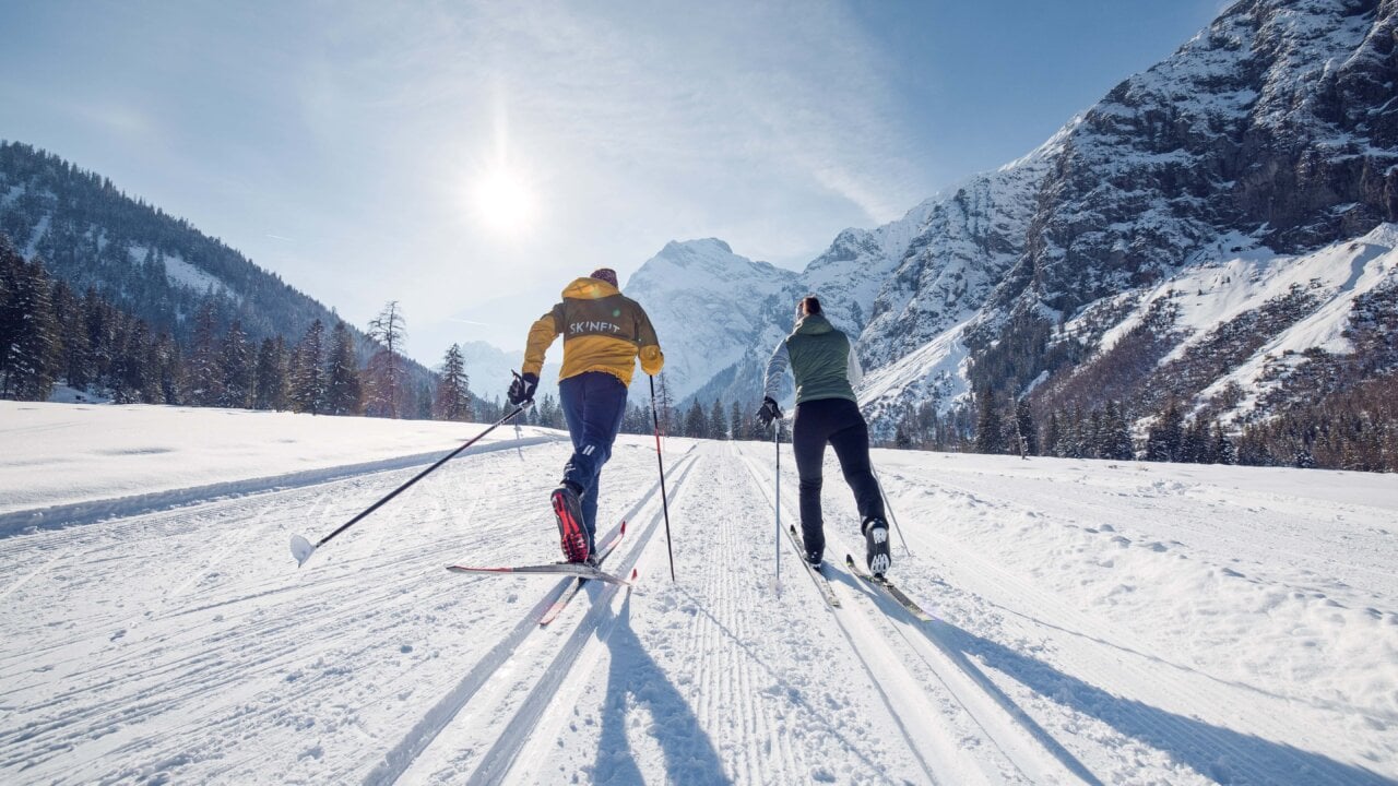 Skifahrer im Schnee vor Berglandschaft.