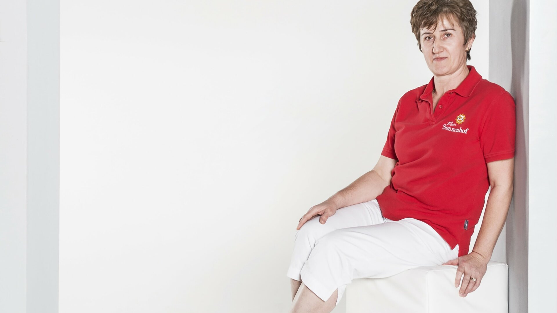 Frau in rotem Shirt sitzt in Nische.