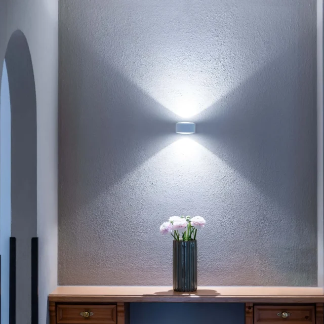 Dekorierte Wand mit Vase und Licht.