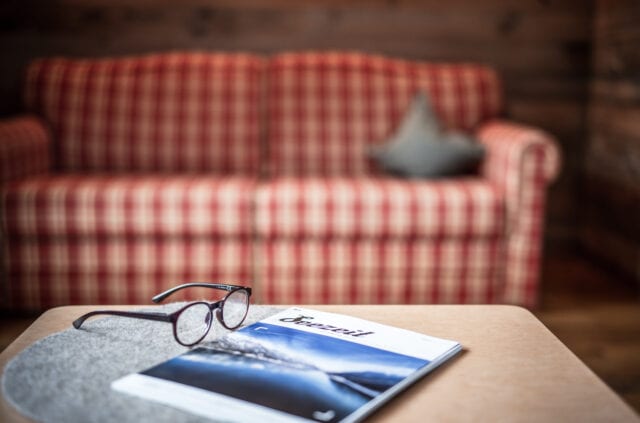 Brille und Zeitschrift auf Tisch vor Sofa