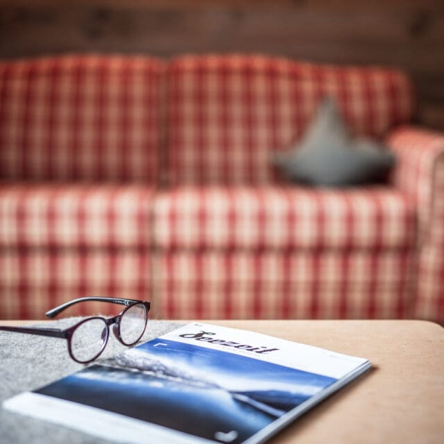 Brille und Zeitschrift auf Tisch vor Sofa