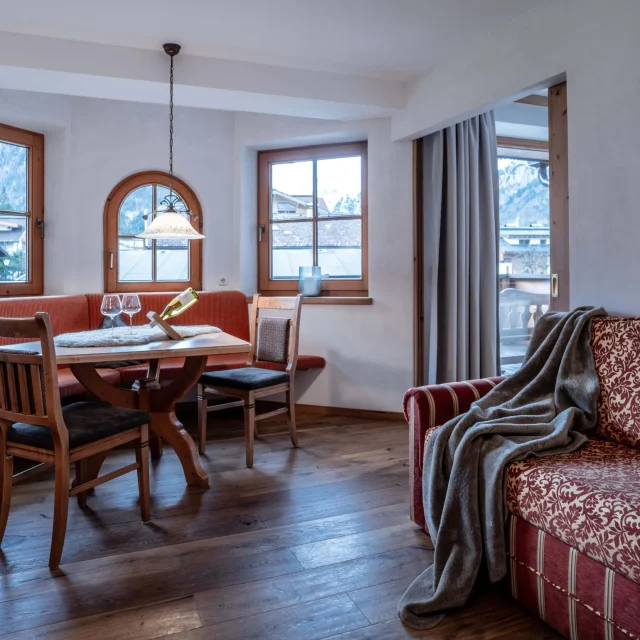 Gemütliche Wohnzimmer-Ecke mit Holz-Esstisch und Sofa.