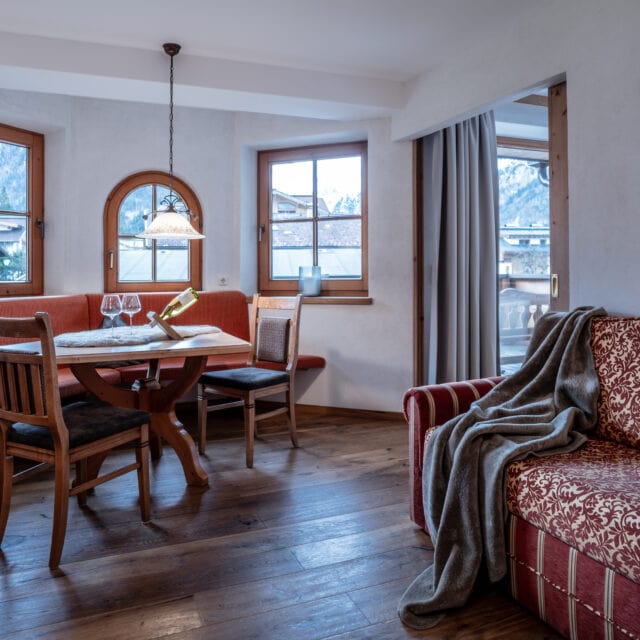 Gemütliche Wohnzimmer-Ecke mit Holz-Esstisch und Sofa.