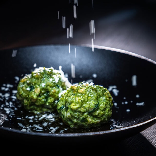 Grüne Bällchen mit Salz in schwarzem Teller.