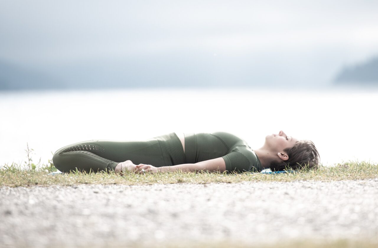 Frau entspannt am Wasser im Yoga-Stil.