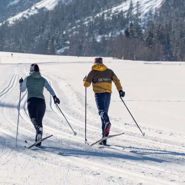 Langlaufende Personen auf verschneiter Strecke.